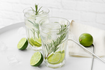Tray with glasses of tasty lime lemonade with rosemary on light background, closeup