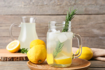 Mason jar of tasty lemonade with rosemary on wooden background