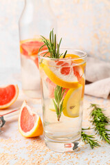 Glass of tasty grapefruit lemonade with rosemary on light background