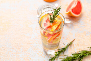 Glass of tasty grapefruit lemonade with rosemary on light background, closeup