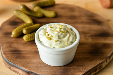 Bowl with tasty tartare sauce and pickled cucumbers on color background, closeup