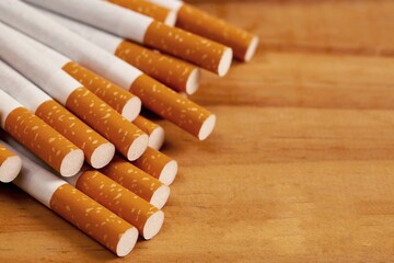 Several cigarettes are stacked on a brown wooden floor and are dangerous for smokers.