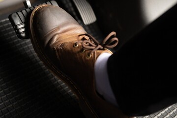 A man in brown leather shoes is stepping on the accelerator. - obrazy, fototapety, plakaty