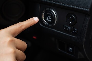 Woman pressing the start button of her car