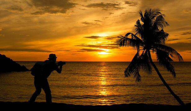 Silhouette of a photographer taking a picture view of the sea at sunset.