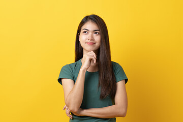 beauty asian teenager in green tee shirt thinking / imagination / question isolated on yellow background in studio. Banner size and have a copy space for text.