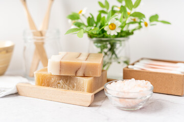 Natural bathroom and home spa tools. Zero waste sustainable lifestyle concept. Bamboo toothbrush, natural soap bar in wooden soap dish, cotton pads, flowers, cotton swabs. White background, copy space