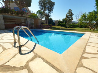 Beautiful old swimming pool in summer season. Blue tiles. Garden and pool view. Vacation time