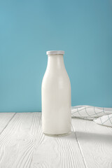 Milk in glass bottle and napkin on white wooden table. Bottle of milk on blue background with copy space. World milk day.