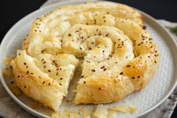 Homemade Balkan Pie with Feta and Sesame Seeds on a plate, side view. Closeup.