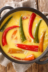 Ema Datshi, the national dish of Bhutan is a deliciously spicy stew made of chili peppers, onions and locally produced yak cheese closeup in the pan on the table. Vertical top view from above