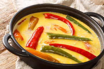 Spicy Ema datshi the national dish of Bhutan is an easy to make hearty soup with chilli peppers and cheese closeup in the pan on the table. horizontal