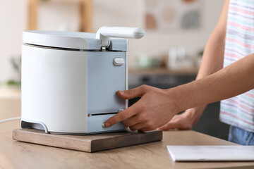 Young man using deep fryer in kitchen, closeup