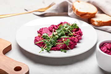 Plate with tasty beet hummus and fresh sprouts on light background
