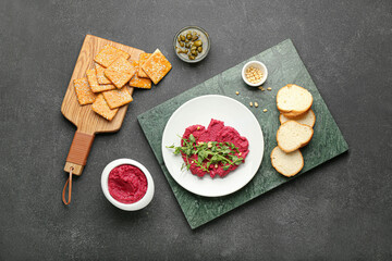 Fototapeta na wymiar Composition with tasty beet hummus, bread and crackers on dark background