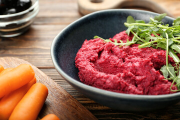 Bowl with tasty beet hummus and fresh sprouts on wooden background, closeup