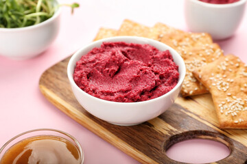 Board with tasty beet hummus and crackers on color background, closeup