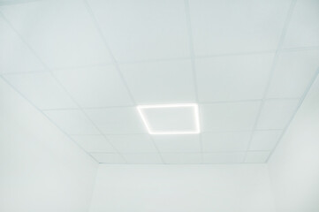 Photo of office room fake ceiling with light, empty white room with neon lights and white walls