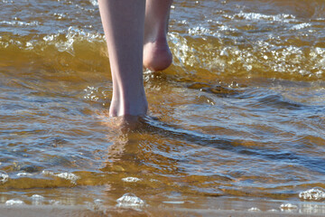 Girl feet and legs walking on water waves