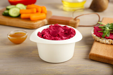 Bowl with tasty beet hummus on grey wooden background