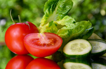 Tomato, cucumber, salad on a bright green background stock images. Mix of fresh vegetables on a natural green background stock photo. Juicy sliced vegetables images