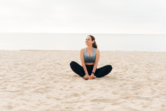 Photo of woman practices yoga and meditates in the lotus position on the beach