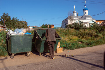 a homeless man rummaging in a trash can