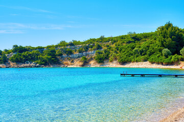 Turquoise sea, green hill and a pier at Demircili bay in Urla, İzmir, Turkey