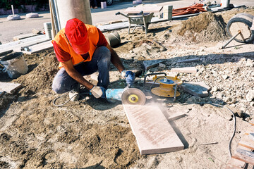 Pavement construction worker using an angle grinder for cutting the tiles