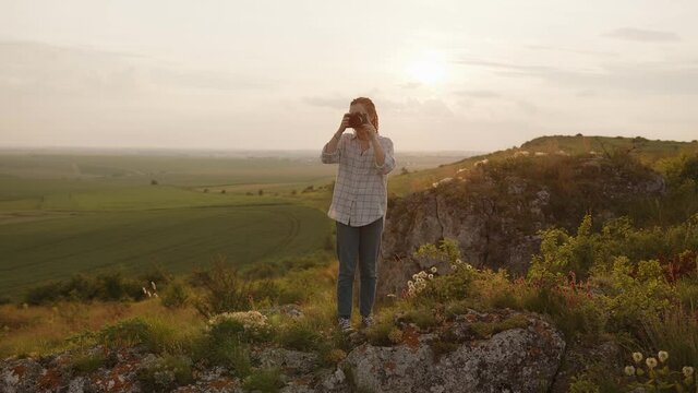 Girl stands on a high mountain and takes photos