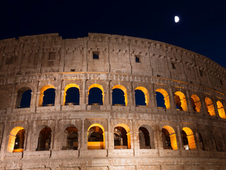 View of the ruins of the Roman Colosseum against the dark blue moonlit night sky. Rome, Italy