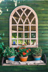 Fototapeta na wymiar Decorative arched window mirror hanging on a wooden wall. Country style decoration.
