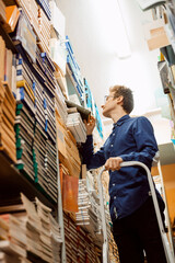 Young intelligent man looking for science materials in the local archive, prepare to write master work. University, academic work, bookworm.