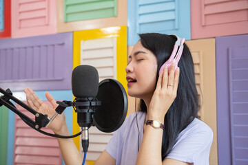 singer wearing headphones singing using microphone against colored wooden wall background