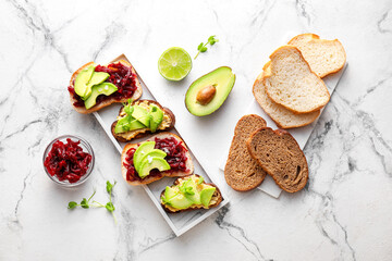 Tasty bruschettas with avocado and beetroot on light background