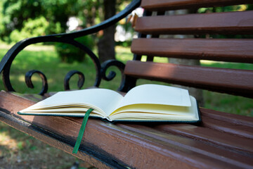 The book is on the bench. There is a diary on a wooden bench in the park.