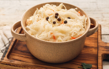 Pot with tasty sauerkraut on light wooden background