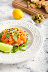 Delicious salmon tartar on marble table, closeup