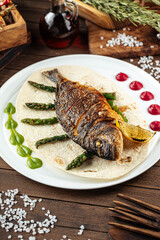 Dish of gourmet grilled dorada fish on the wooden background