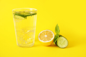 Glass with cucumber lemonade on color background