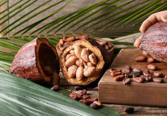 Fresh cocoa fruit, beans and palm leaf on wooden background