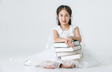Portrait studio shot of Asian pretty girl wears white princess long rose flower dress fashion costume posing with stack of books on white background
