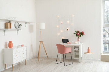 Comfortable workplace with laptop and protea flowers in interior of room