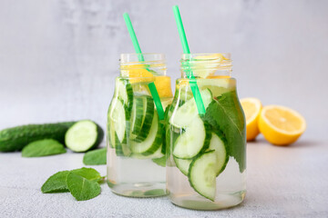 Bottles with cucumber lemonade on light background