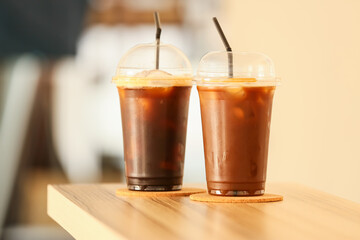 Plastic cups with tasty iced coffee on wooden table