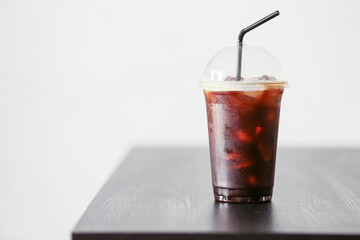 Plastic cup with tasty iced coffee on light background
