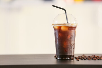 Plastic cup with tasty iced coffee on table