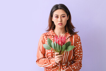 Beautiful young woman with protea flower on color background