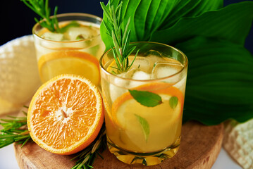 Lemonade with orange, rosemary and mint in glass on table. Summer fresh drink