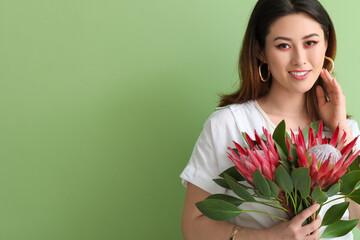 Beautiful young woman with protea flowers on color background